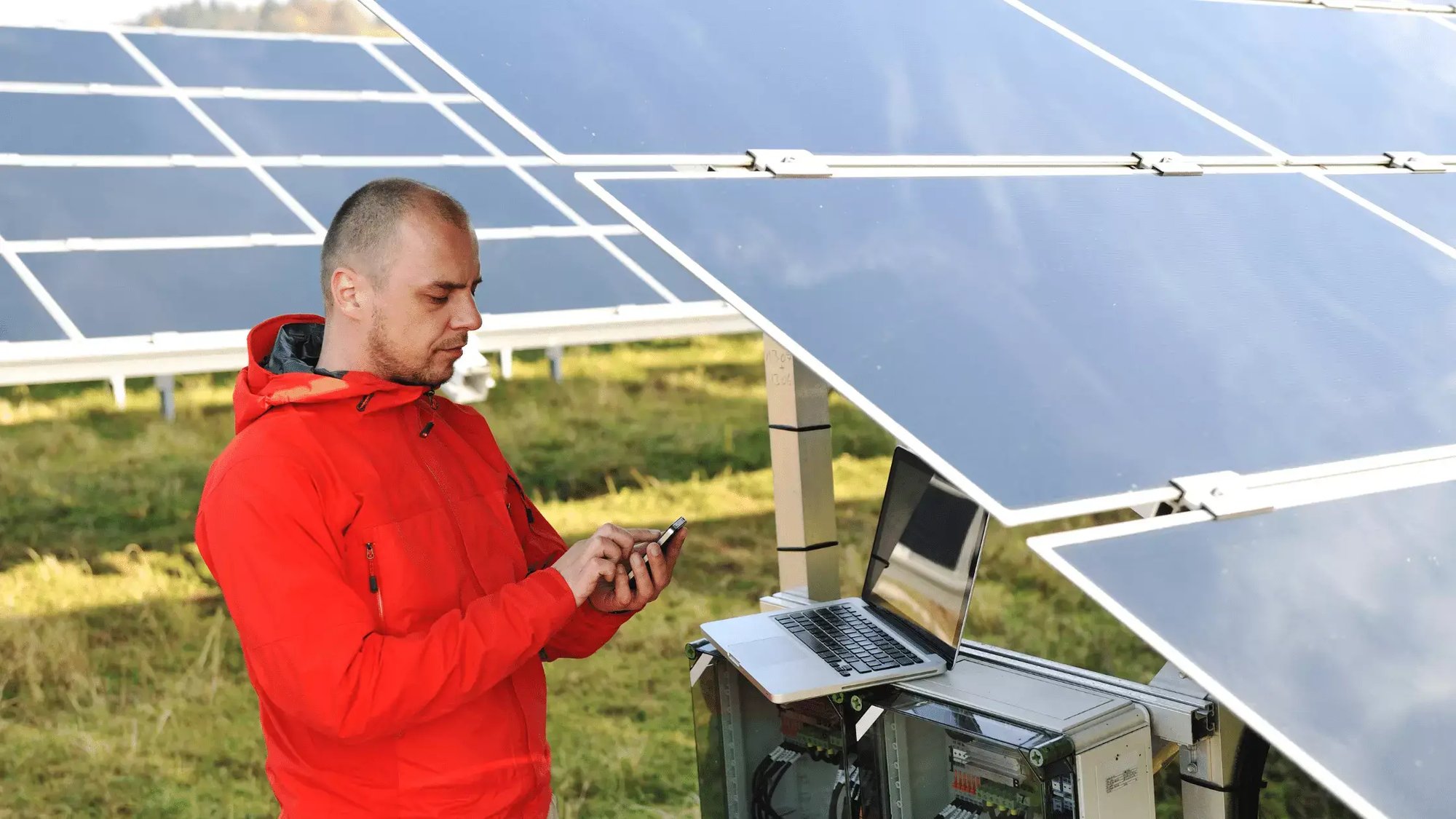 business man engineer using laptop at solar panels plant eco energy field  in background