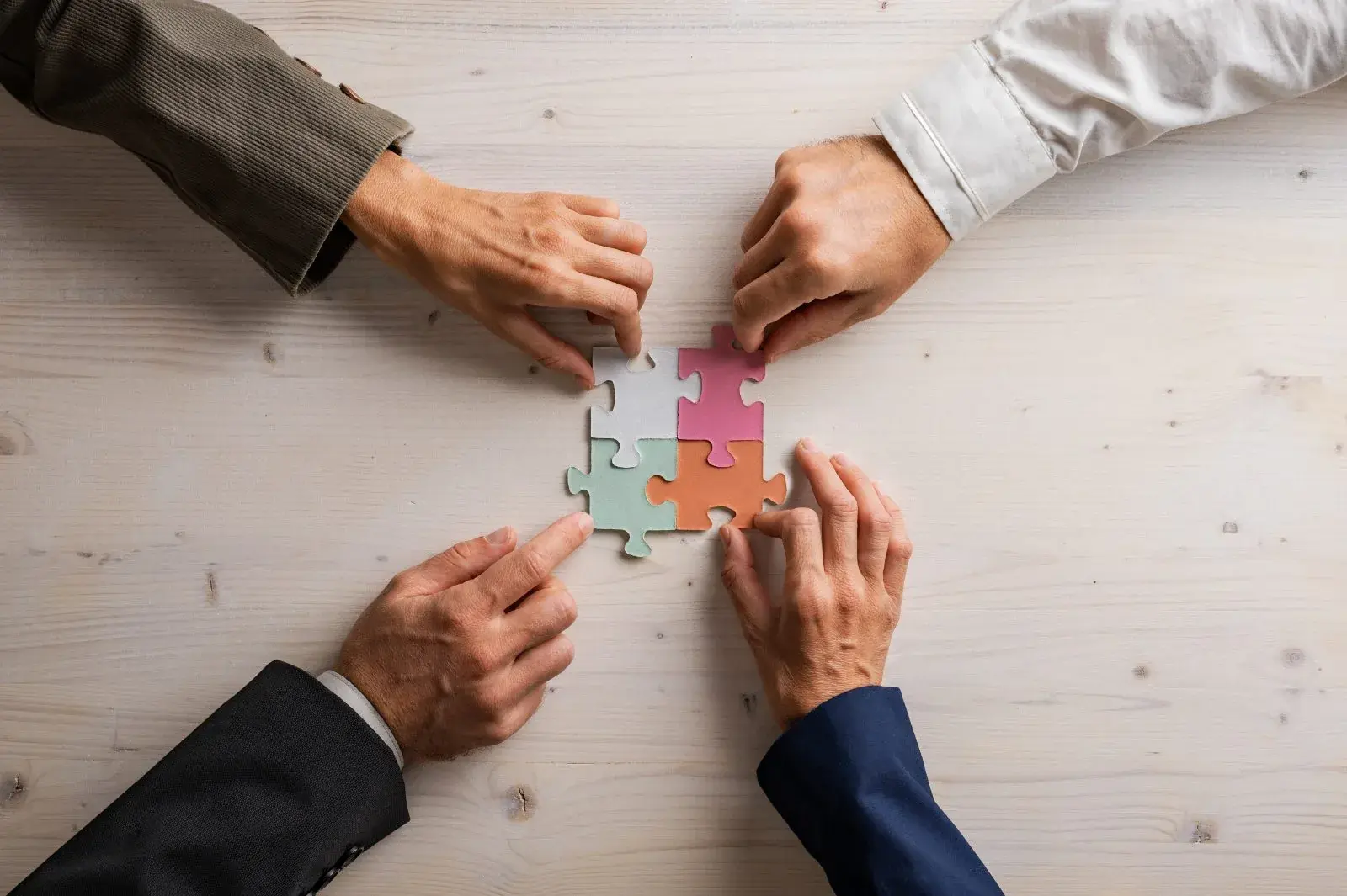 Four people connecting colourful puzzle pieces together